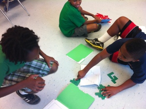 3 students working on math problem-solving on the floor